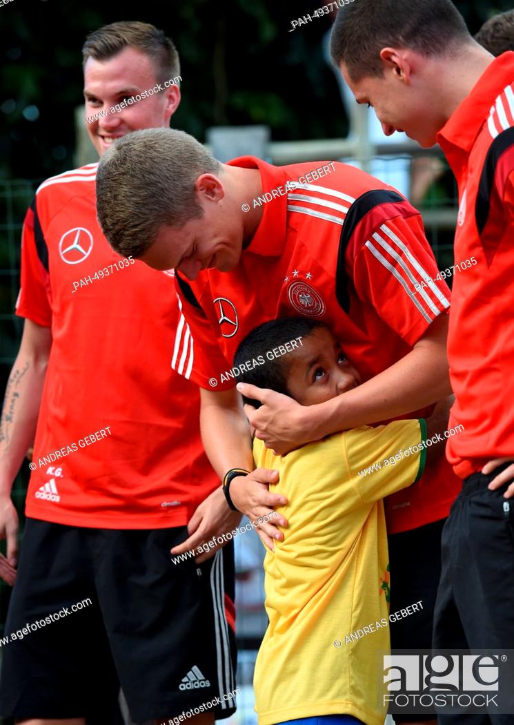 Stock Photo: Matthias Ginter (C) of the German national team hugs a school child during their visit to the primary school in Santo Andre, Brazil, 11 June 2014.
