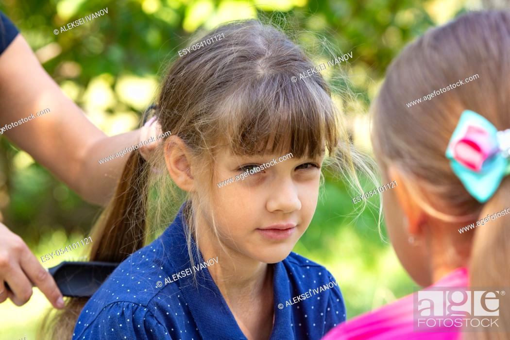 Stock Photo: Girl trying to comb the girl's tightly tangled hair.