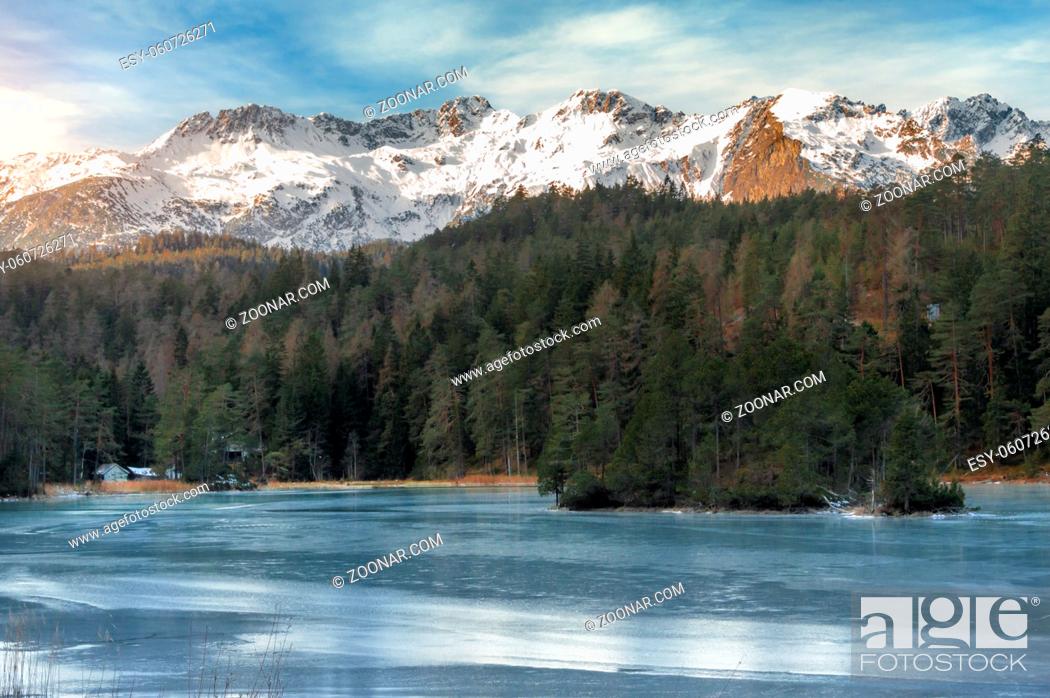 Stock Photo: Winter landscape with a frozen lake surrounded by green fir forest and the snowy peaks of the Alps mountains, near Biberwier village, Austria.