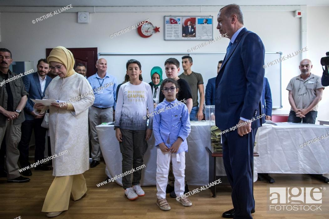 Stock Photo: Turkish President Tayyip Recep Erdogan (R) looks on as his wife Emine Erdogan enters a voting booth to cast her ballot in Turkey's elections at a polling.