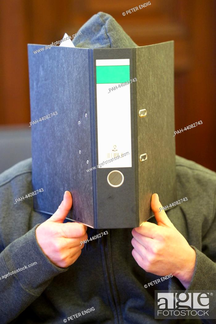 Stock Photo: The defendant Jan Julius N. covers his face before the verdict in the Land court in Leipzig, Germany, 15 November 2013. In May 2013 the 34 year old attacked a.
