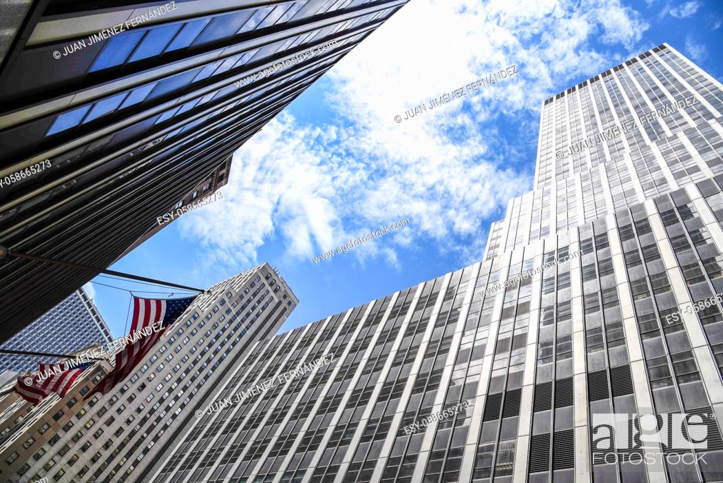 Stock Photo: Low angle view of American flag and skyscrapers against sky in New York City. Finance, business and technology background.