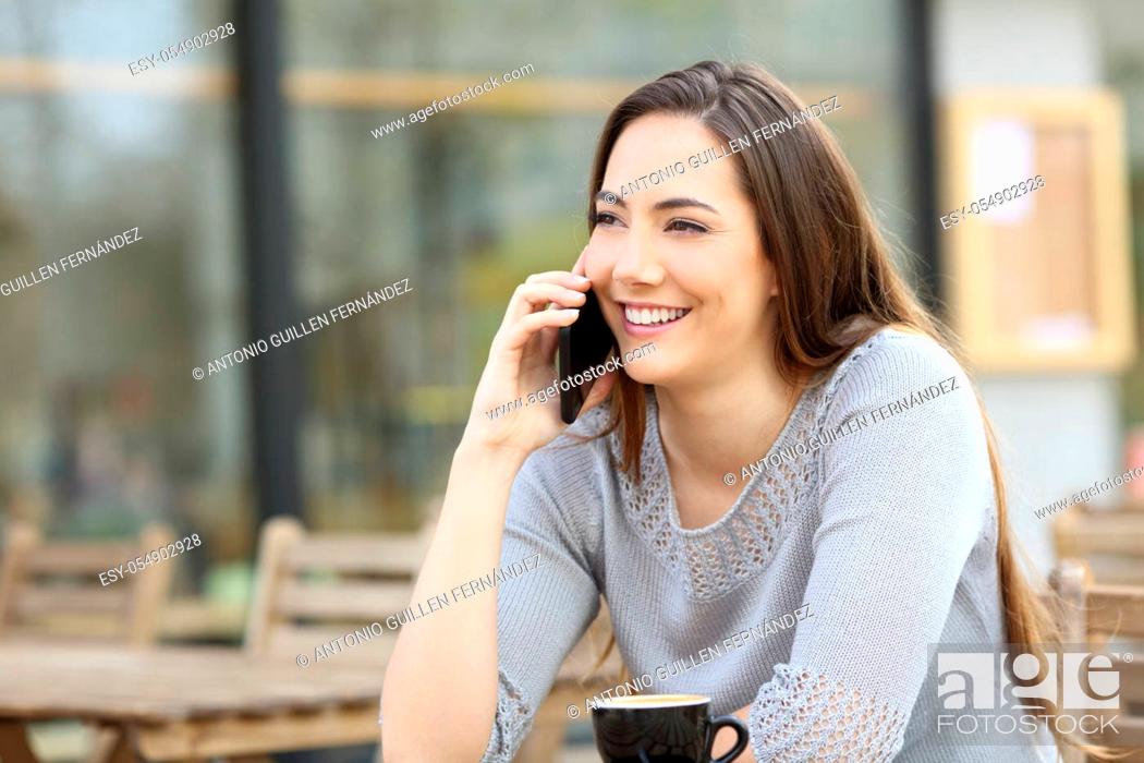 Stock Photo: Happy young woman talking on the smart phone in a coffee shop terrace.