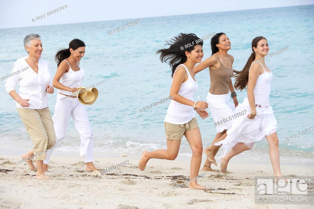 Photo de stock: Diverse women running on beach together.