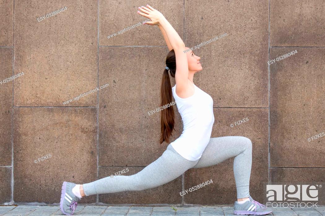 Stock Photo: Sporty attractive girl practicing yoga, standing in Horse rider exercise, anjaneyasana pose, working out, wearing sportswear, outdoor full length.