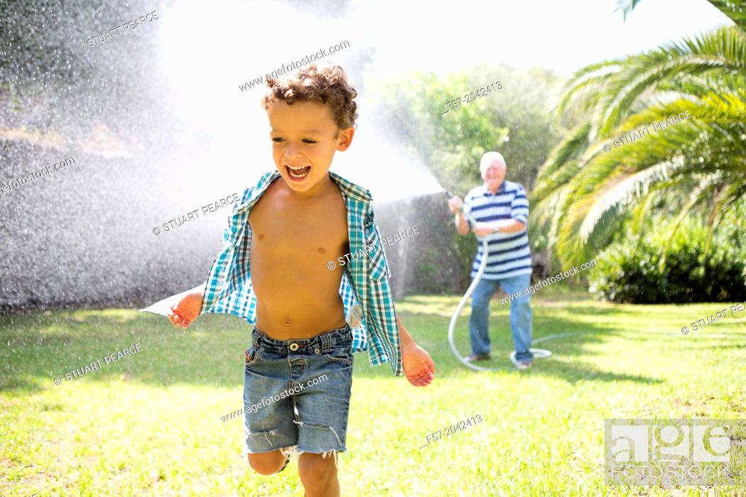 Stock Photo: Young boy playing with his grandfather in the garden.