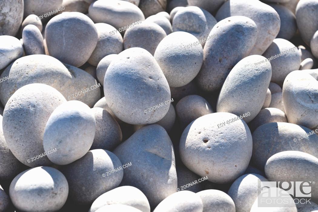 Stock Photo: Close up of rounded bright white and grey stones at a sunny beach.