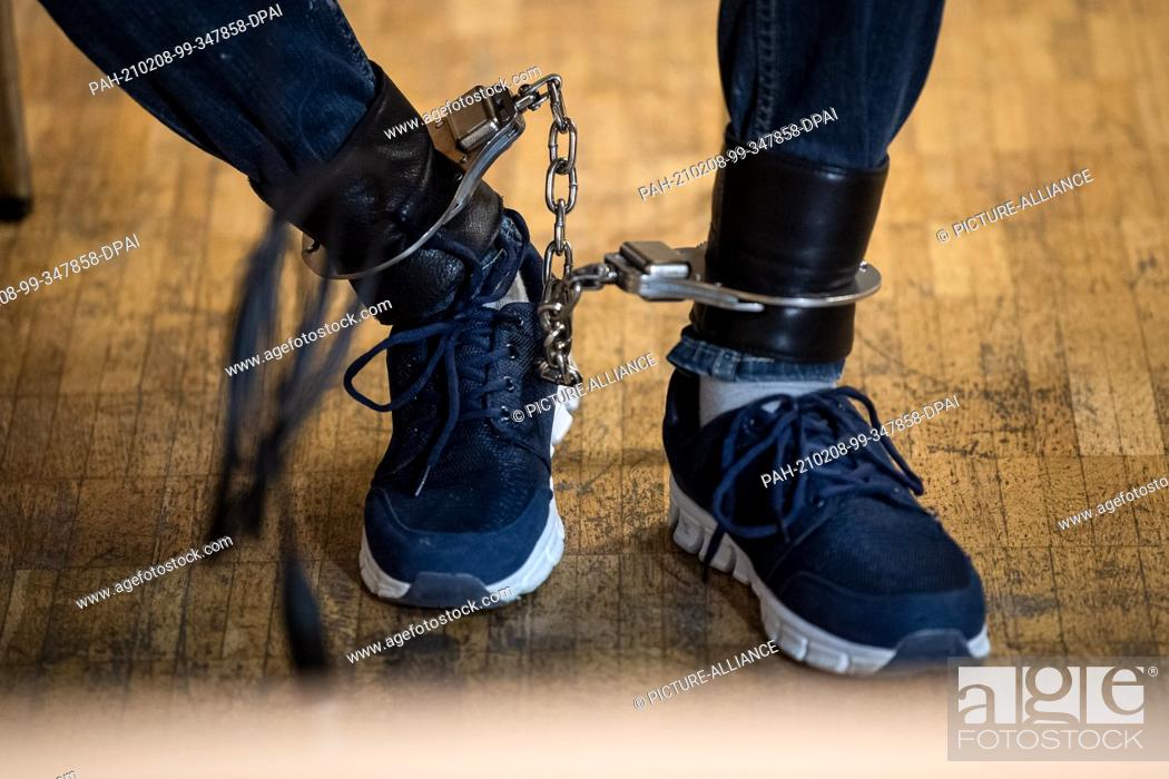 Stock Photo: 08 February 2021, Lower Saxony, Verden: One of the defendants sits with ankle bracelet before the start of the trial in the town hall of Verden.