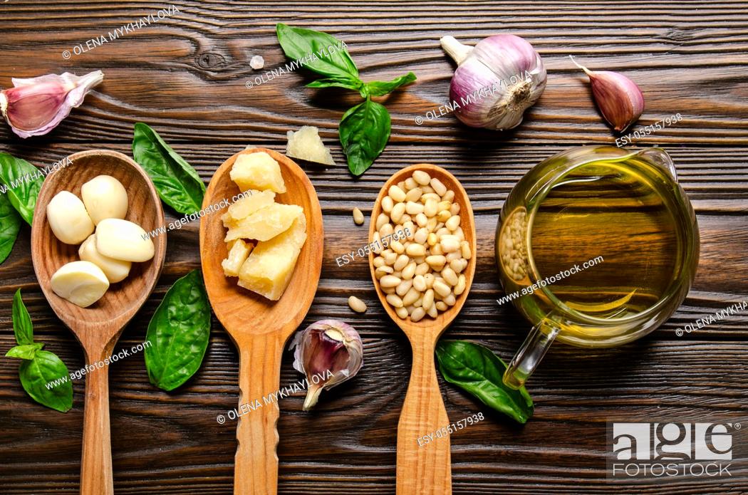 Stock Photo: Flat lay view at wooden spoons with food ingredients for pesto genovese sauce on kitchen table.