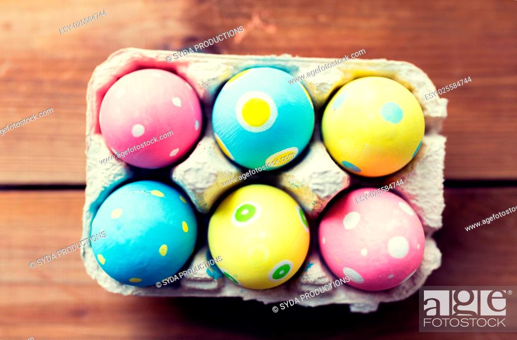 Stock Photo: easter, holidays, tradition and object concept - close up of colored easter eggs in egg box or carton wooden surface.