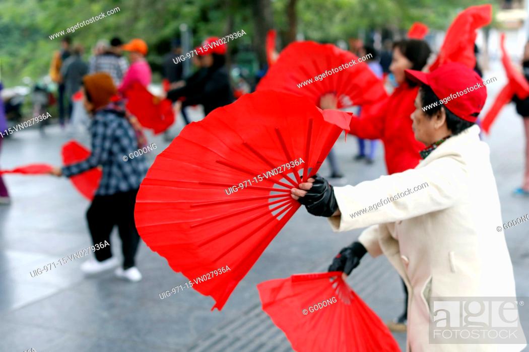 Stock Photo: Early morning tai chi session along the banks of Hoan Kiem lake. Exercises with fans. Hanoi, Vietnam.