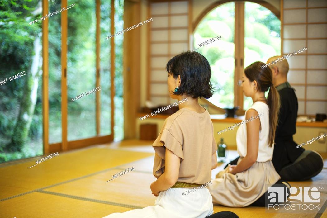 Stock Photo: Two Japanese women and Buddhist priest kneeling in Buddhist temple, praying.