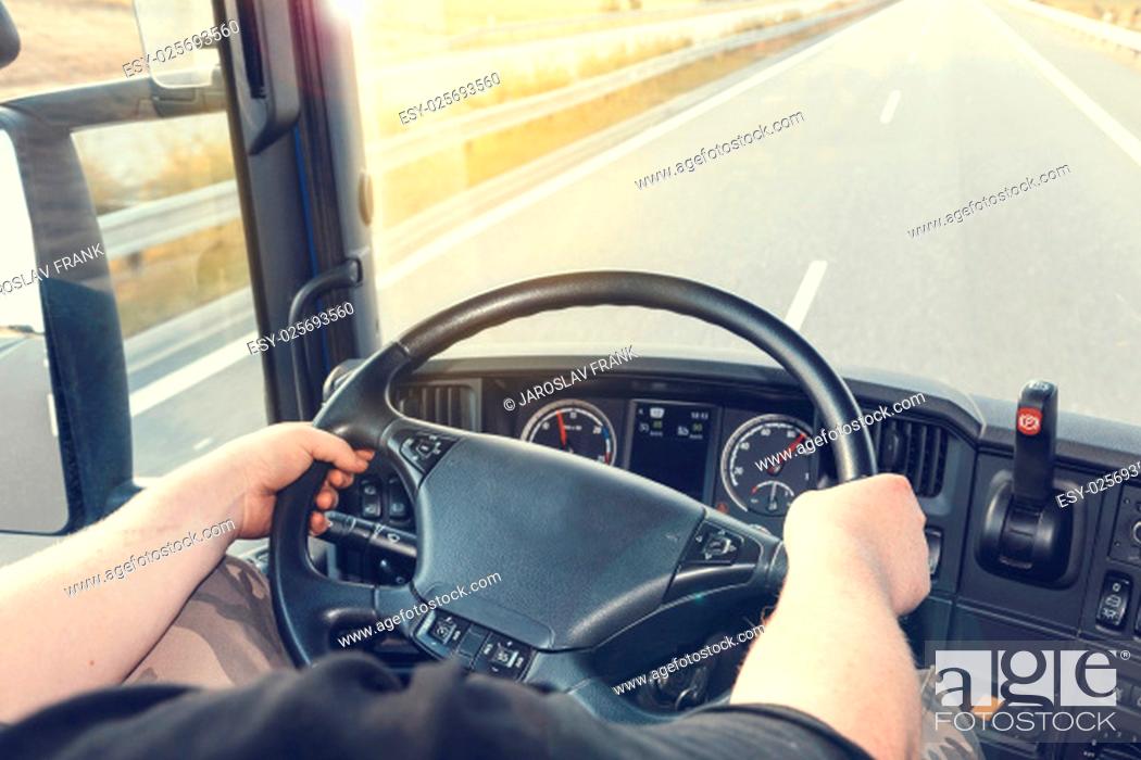 Stock Photo: View on the dashboard of the truck driving. The driver is holding the steering wheel. Empty highway is in front of the car.