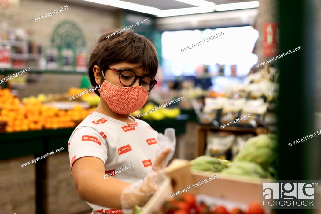 Stock Photo: Boy taking vegetables in supermarket.