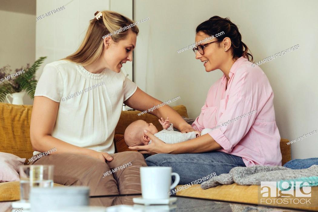 Stock Photo: Midwife and mother giving newborn baby a belly massage to help with digestion.