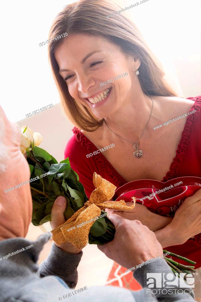 Stock Photo: Senior man giving woman bunch of flowers and chocolates.
