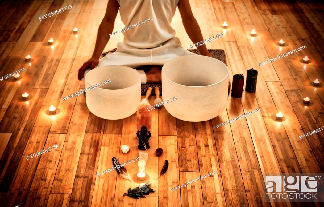 Stock Photo: Man sitting in indian behind his two musical crystal bowls, with a display of sacred object and surrounded by candles.