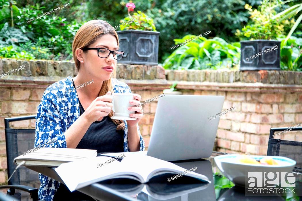 Stock Photo: Pregnant mid adult woman looking at laptop on patio table.