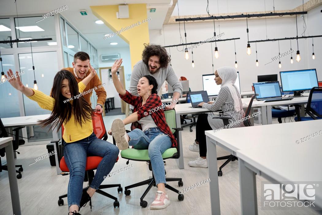 Stock Photo: business people having fun while racing on office chairs.