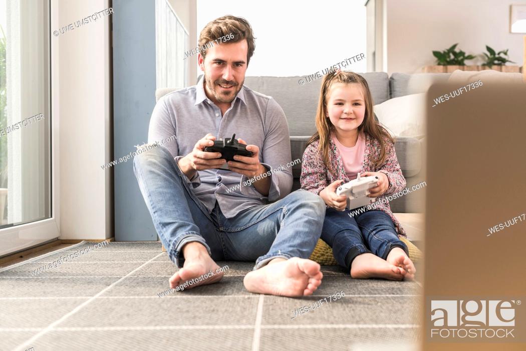 Stock Photo: Young man and little girl playing computer game with gaming console.