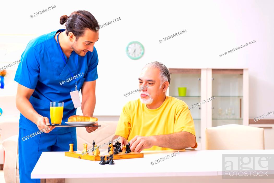 Stock Photo: The young male doctor visiting old patient at home.