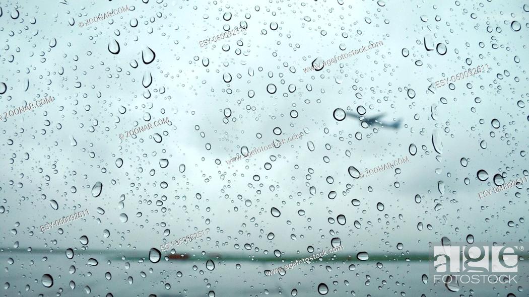 Stock Photo: raindrops background on airport window with flying plane behind.