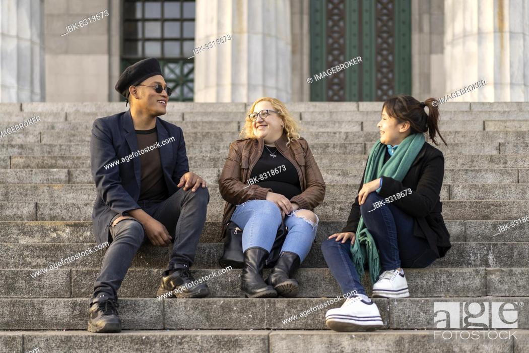 Stock Photo: Multi ethnic group of friends sitting on some stairs having a good time chatting and laughing.