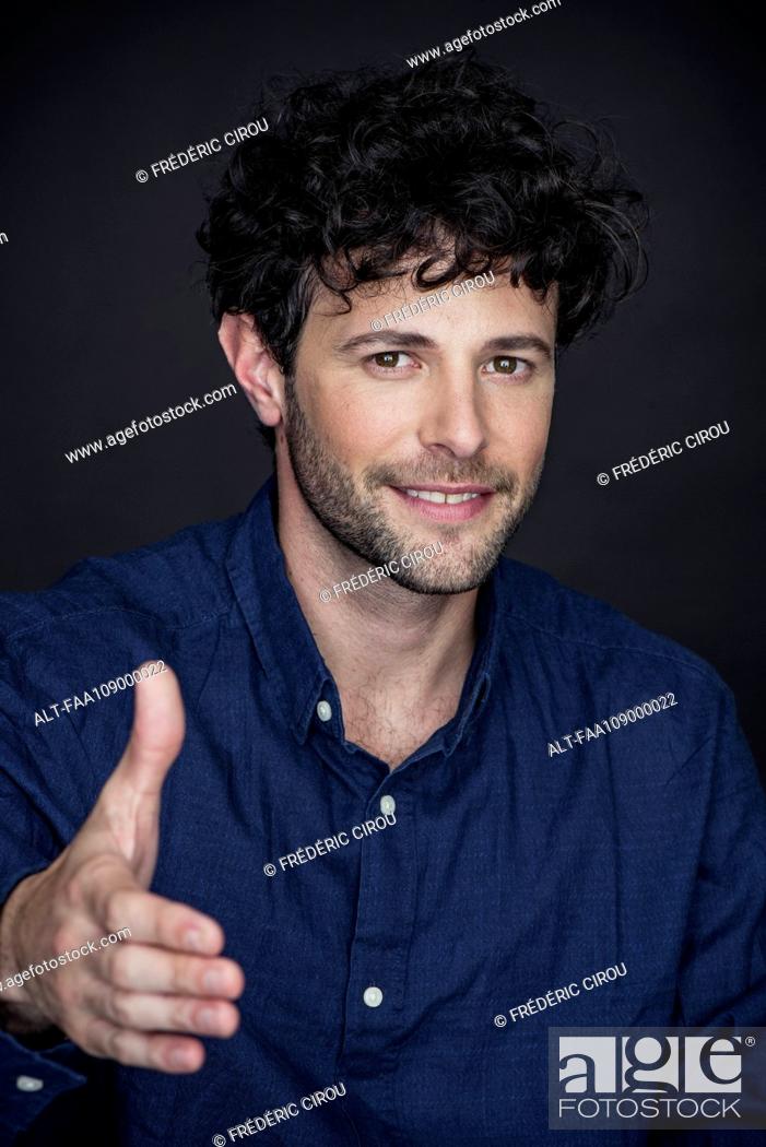 Stock Photo: Man holding out hand and smiling, portrait.