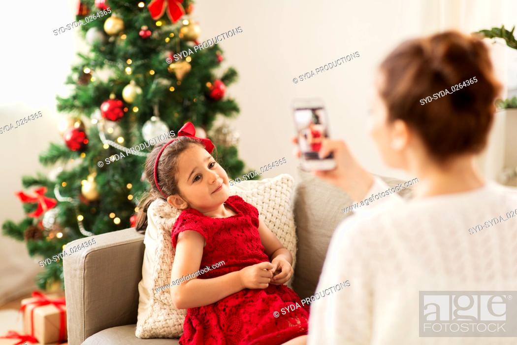 Stock Photo: mother picturing daughter by phone on christmas.