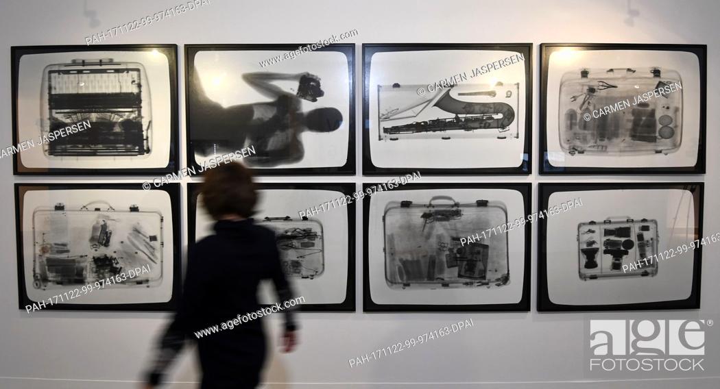 Stock Photo: A participant of the press conference walks past monochrome photographies 'Checked Baggage' by Timm Ulrichs at the Wilhelm Wagenfeld Haus in Bremen, Germany.