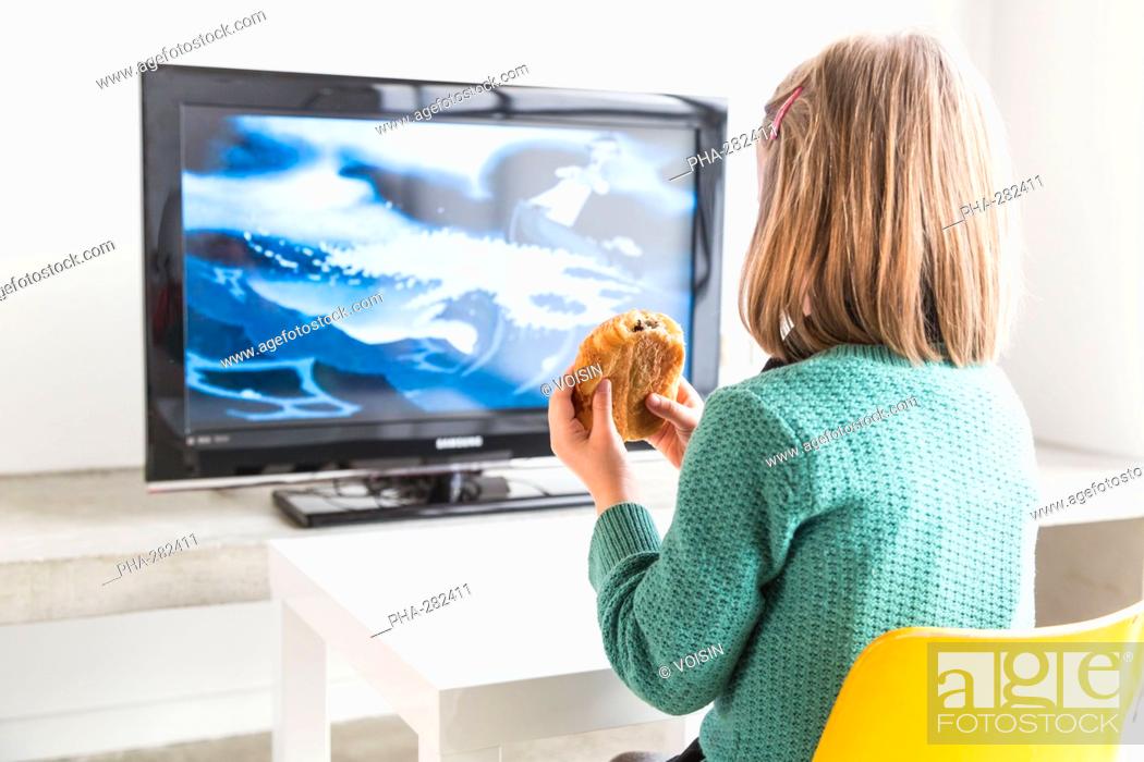 Girl watching TV while eating pastry, Foto de Stock, Imagen Derechos  Protegidos Pic. PHA-282411 | agefotostock