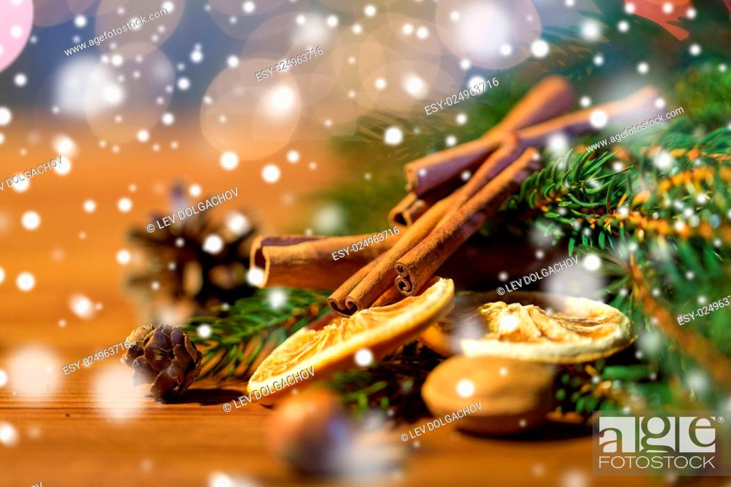 Stock Photo: decoration, winter, holidays and new year concept - close up of christmas fir branch with cinnamon and dried orange on wooden table.