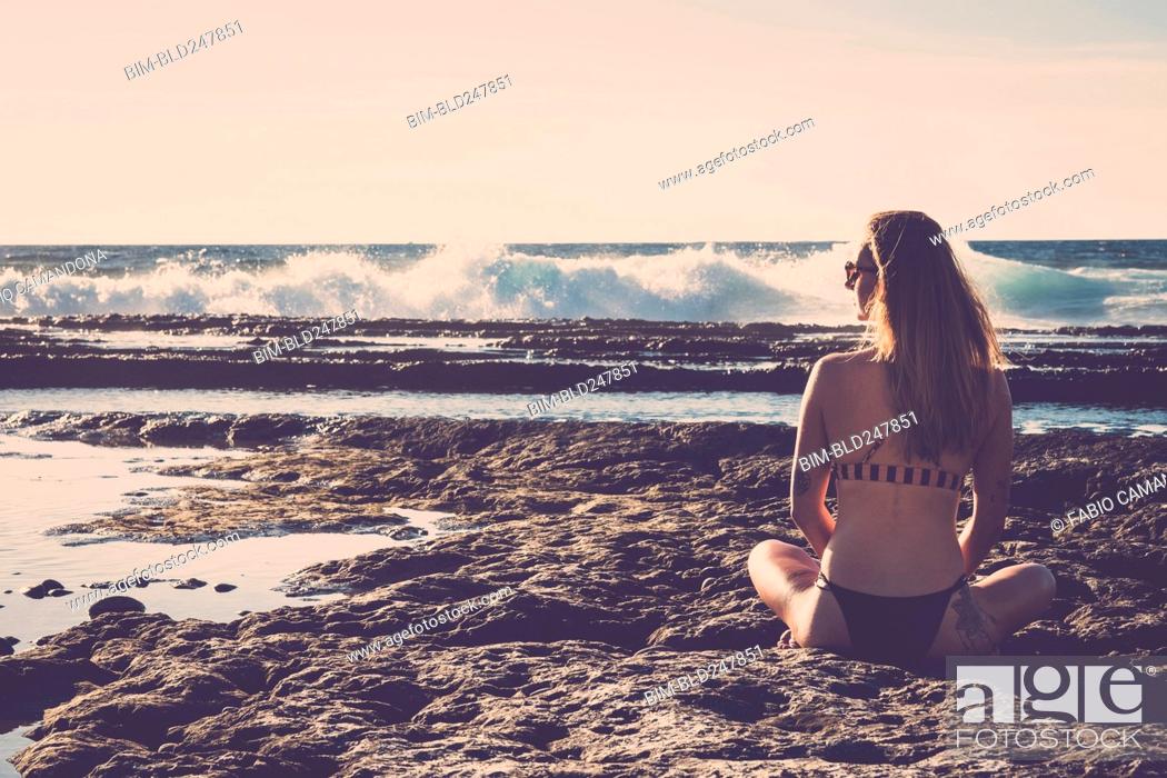 Stock Photo: Caucasian woman sitting on beach wearing bikini.