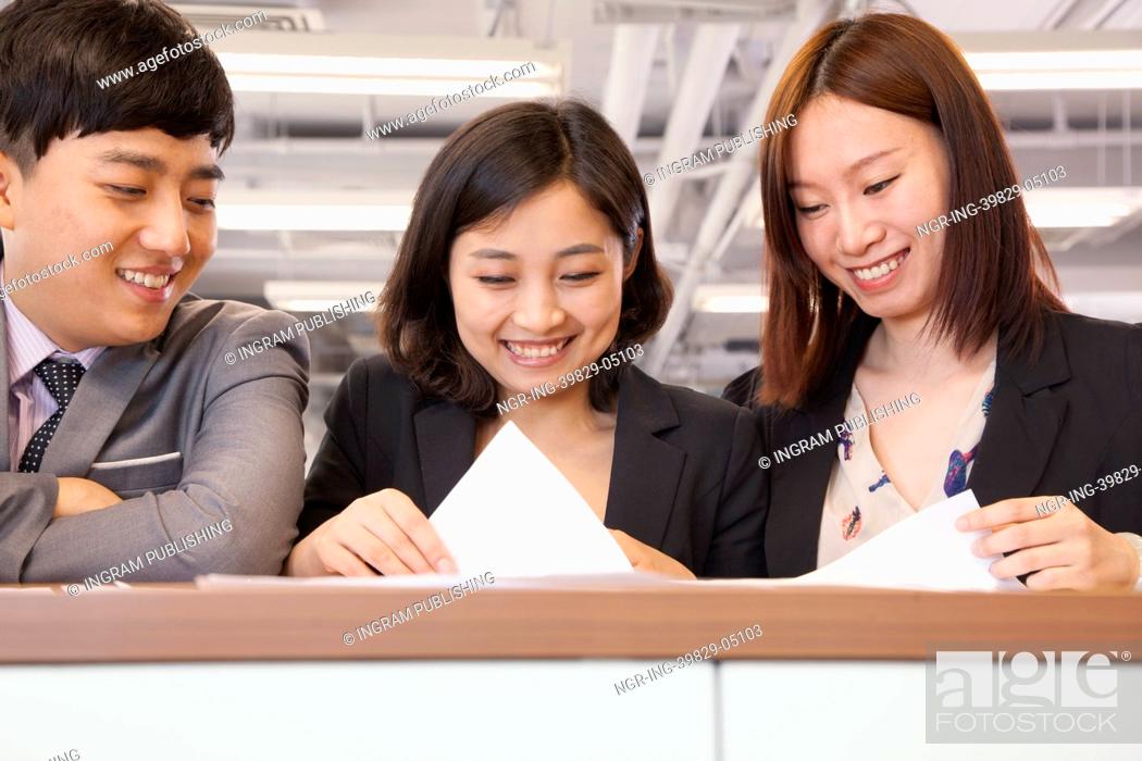 Stock Photo: Office workers working together, looking at documents.