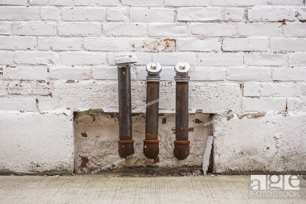 Stock Photo: Three metal pipes attached to the side of a brick building.