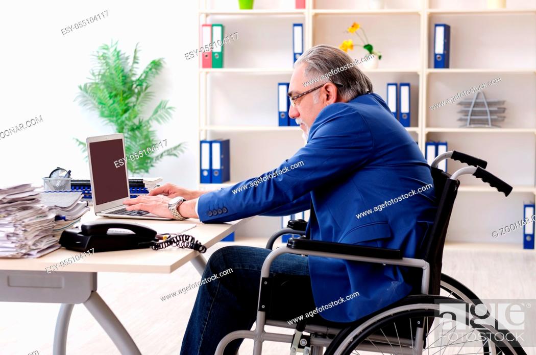 Stock Photo: Aged employee in wheelchair working in the office.