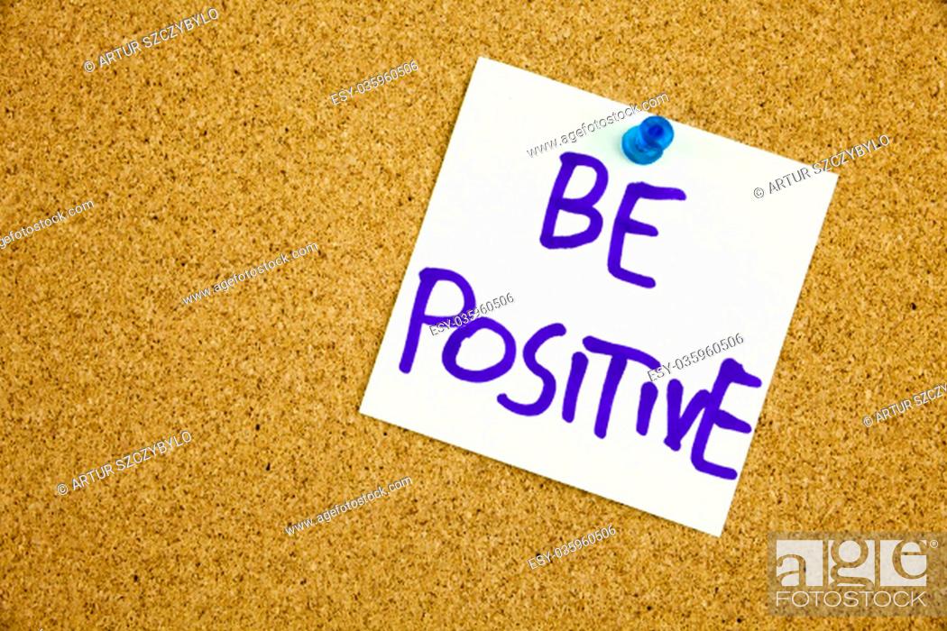 Stock Photo: A yellow sticky note writing, caption, inscription be positive, motivational lifestyle reminders against black ext on a colorful sticky note pinned to a cork.