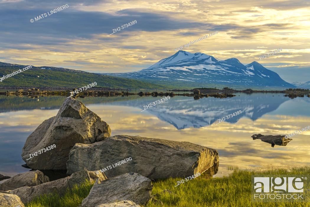 Stock Photo: View over Mount Akka reflecting in the water, big rocks in the foreground, in nice evening light in the summer nigh, Stora sjöfallet nationalpark.
