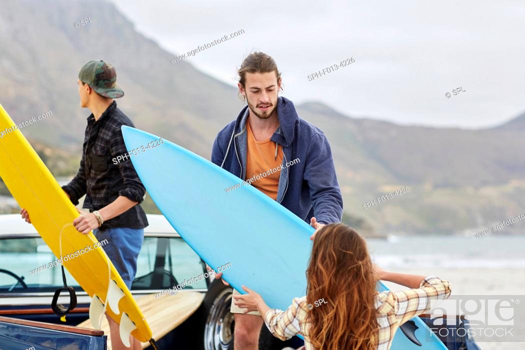 Stock Photo: MODEL RELEASED. Young woman handing surfboard to man.