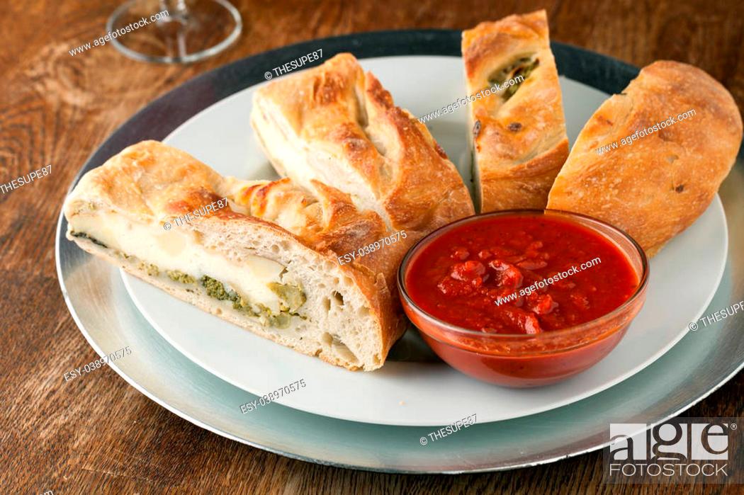 Stock Photo: Homemade stromboli or stuffed bread with broccoli potatoes garlic onions and mozzarella cheese along with a side of marinara dipping sauce.
