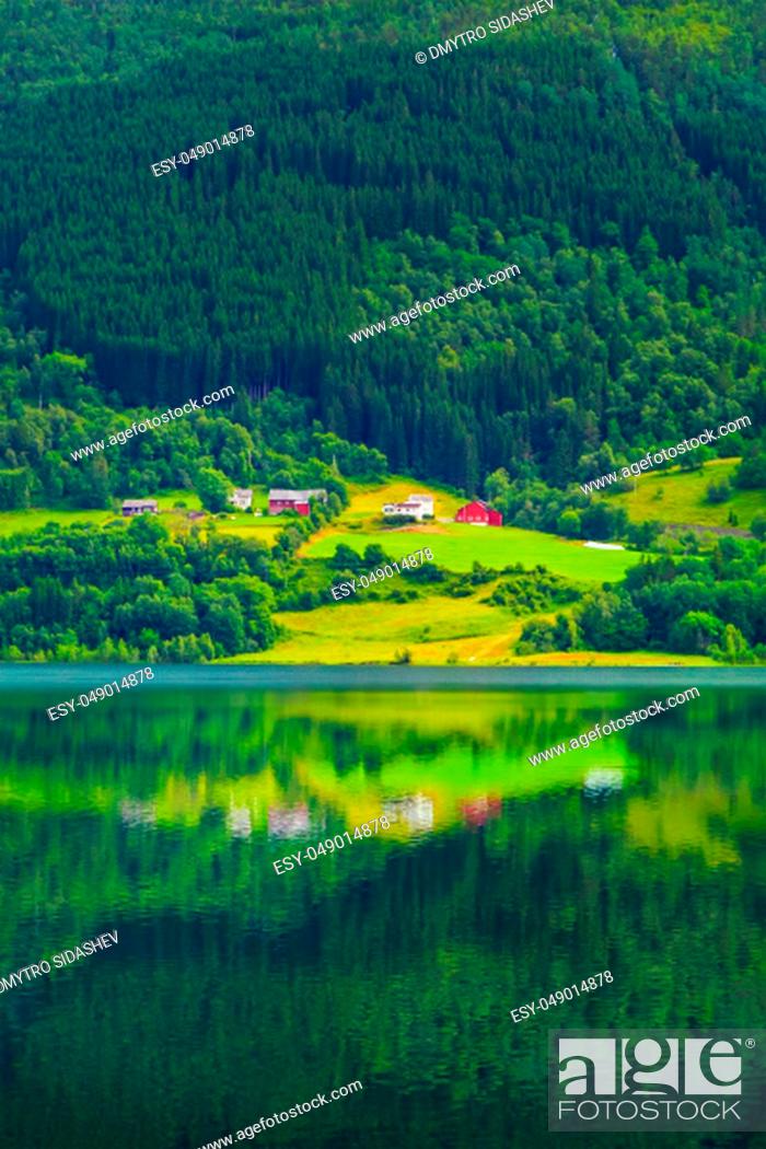 Stock Photo: Colorful village on the shore of alpine lake, at the foot of wooded mountain slope. A small village with modern houses by the lake, Norway.