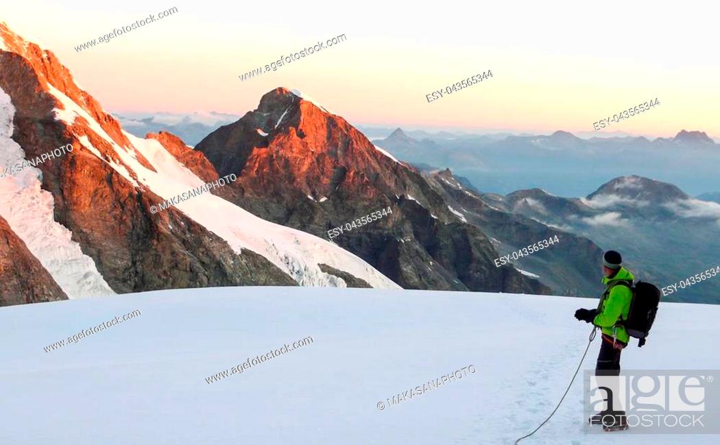 Stock Photo: male mountain guide standing on a glacier on his way to a high summit in the Swiss Alps just after sunrise.
