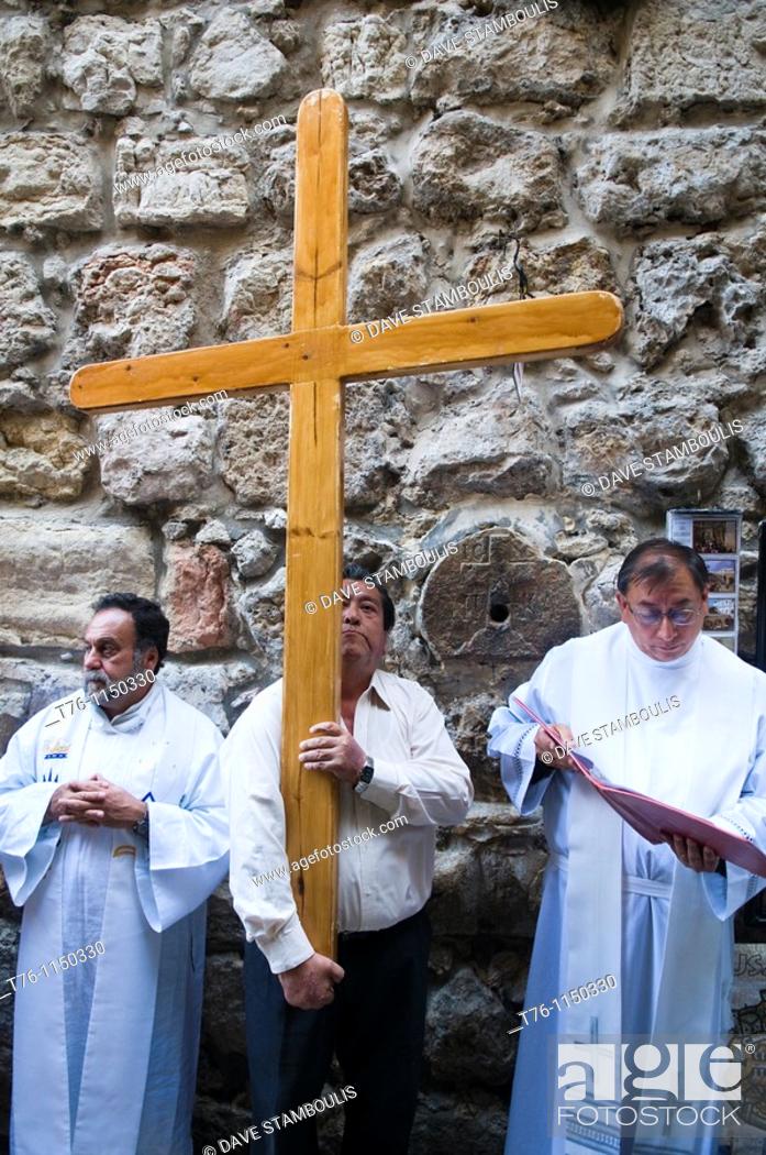 Stock Photo: a pilgrim carries the cross following Jesus' steps on the Via Dolorosa in Jerusalem.