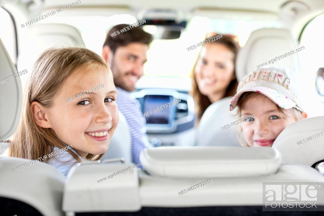Stock Photo: Happy family doing a road trip, looking over shoulder at camera.