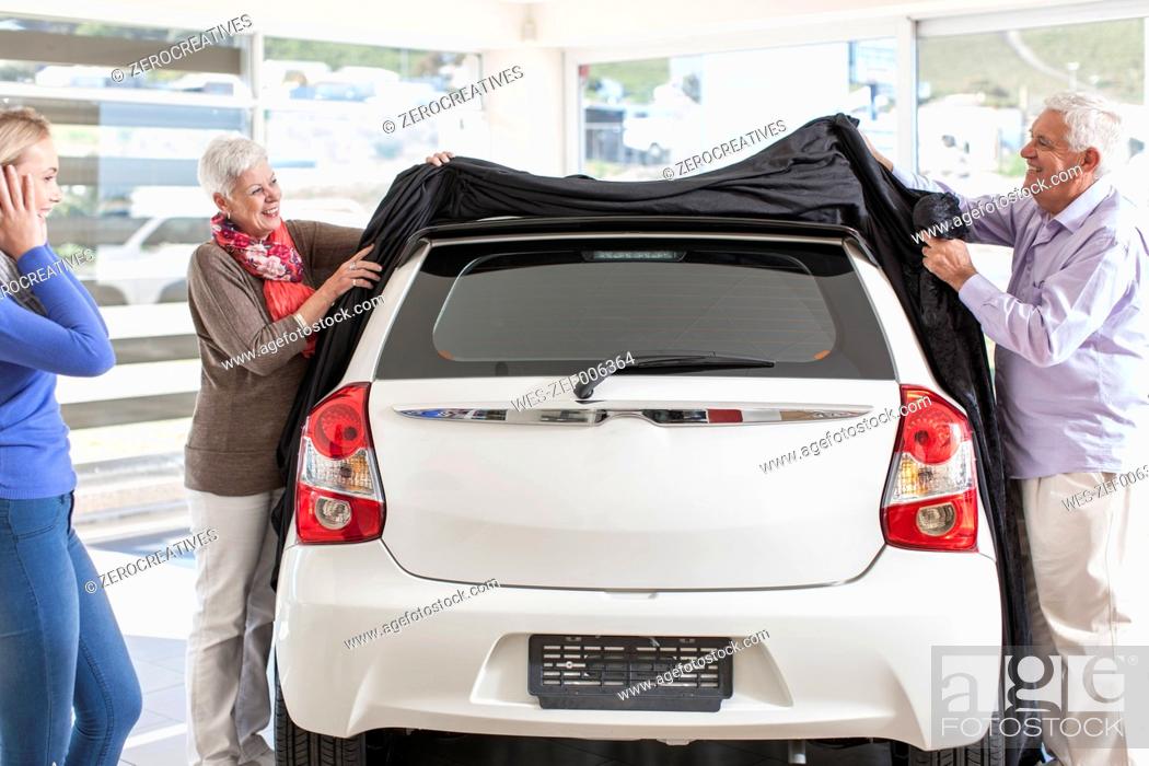 Stock Photo: Father and mother unveiling new car as gift for the daughter.