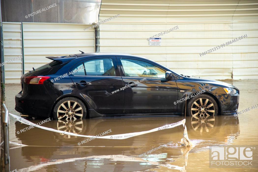 Stock Photo: 13 December 2022, Portugal, Lissabon: A car stands on a flooded street. Heavy rains have caused damage to roads, houses and stores in the Portuguese capital.