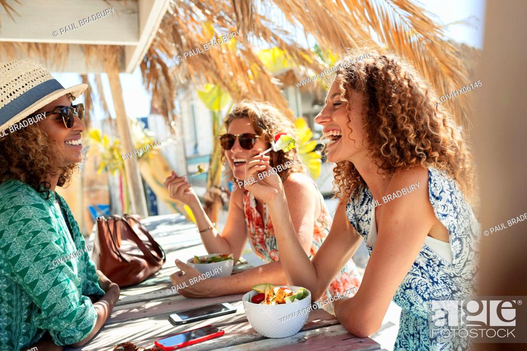 Stock Photo: Happy women friends eating salad at sunny beach bar.
