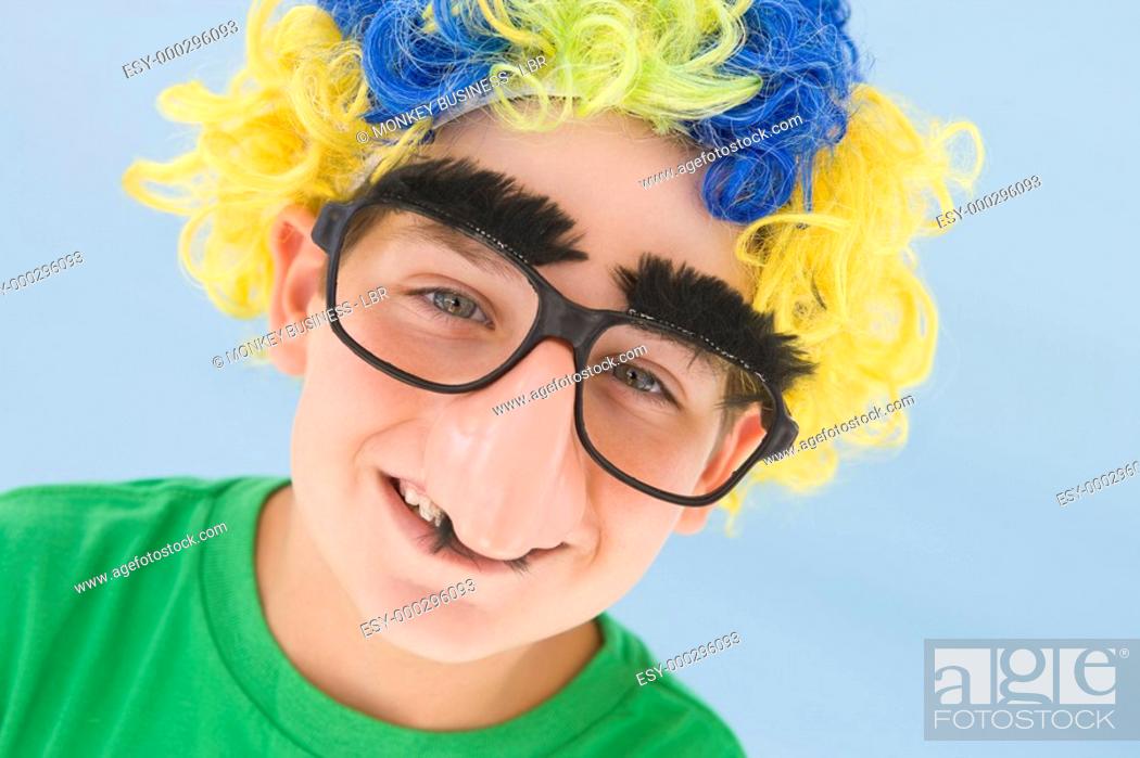 Stock Photo: Young boy wearing clown wig and fake nose smiling.
