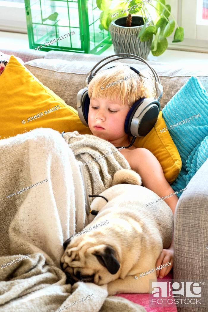 Stock Photo: Boy with headphones on sofa.