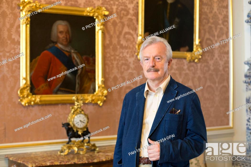 Stock Photo: 26 August 2018, Latvia, Rundale: The art historian and long-time director of the palace, Imants Lancmanis, stands in front of a portrait of the Duke of Kurland.